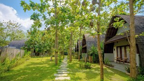 A pathway leading to a building with a sloped roof, surrounded by trees and greenery. - Kayu Jati Cottages (Penida Island)