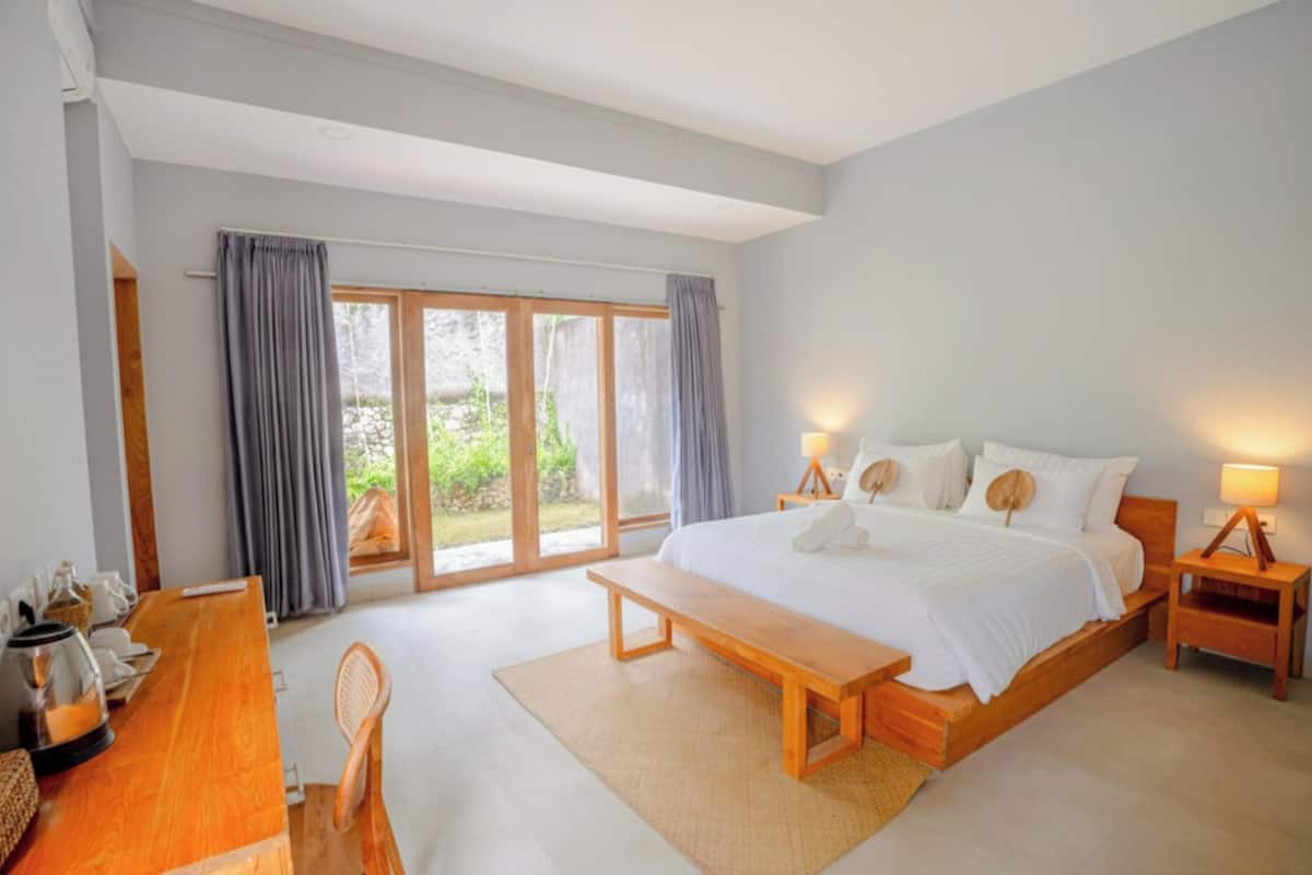 Ein geräumiges Schlafzimmer mit einem großen Bett, einer Holzbank und einem Schreibtisch mit Stuhl.