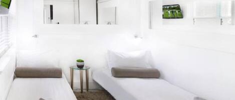 A hotel room with two beds, a small table with a plant, and a window with a view.