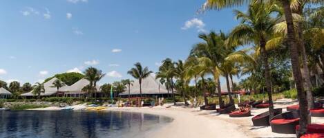 A beach resort with a sandy shoreline, palm trees, and beach chairs.