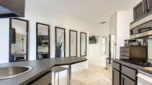 A modern kitchen with a central island, stainless steel appliances, and dark cabinetry. - PgaVillageResort by AmericanVacationLiving 1 Br (Port St. Lucie)