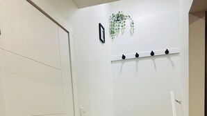 Una escalera con escalones de madera y paredes blancas, un taburete negro pequeño y una planta en la pared.