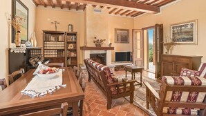Una sala de estar acogedora con chimenea, muebles de madera, una estantería y un comedor con una mesa preparada para dos.