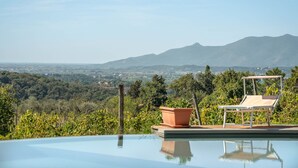 Una piscina infinita con vistas despejadas a un paisaje montañoso y una ciudad distante.