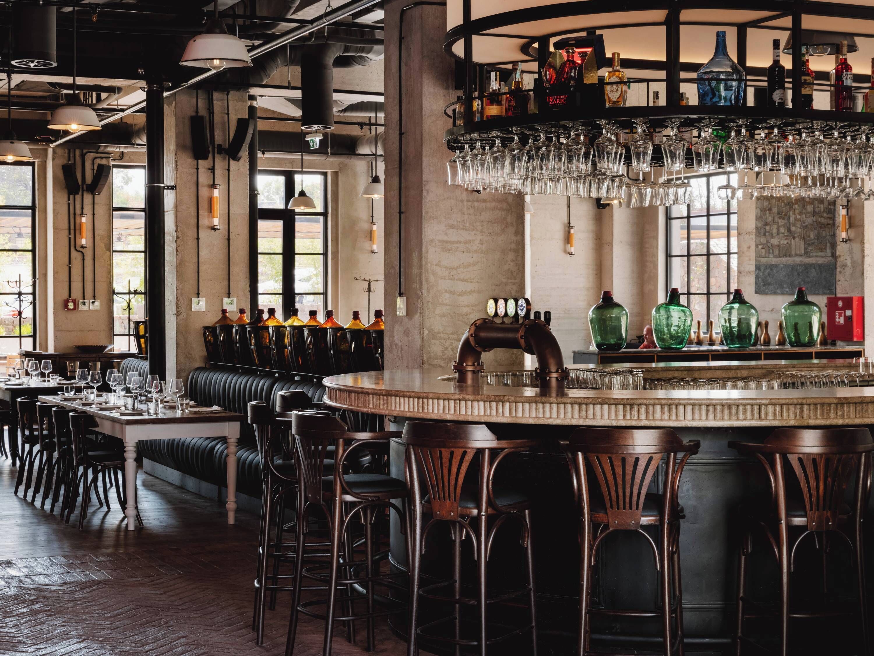 A bar area with a round bar, stools, and a variety of bottles and glasses.