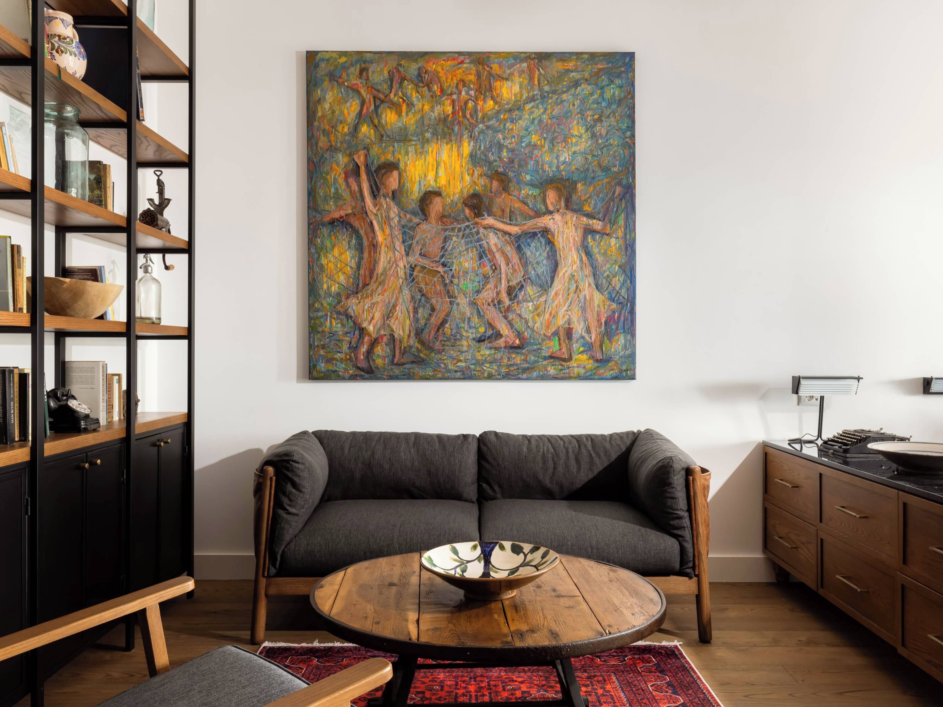 Een woonkamer met een bank, een salontafel, een boekenkast en een schilderij aan de muur.