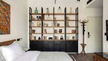 Un dormitorio con una cama grande, una estantería, un perchero y un televisor.