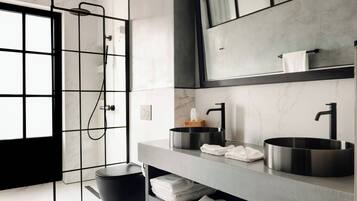 A modern bathroom with a black toilet, a large mirror, and a sink with a black faucet.
