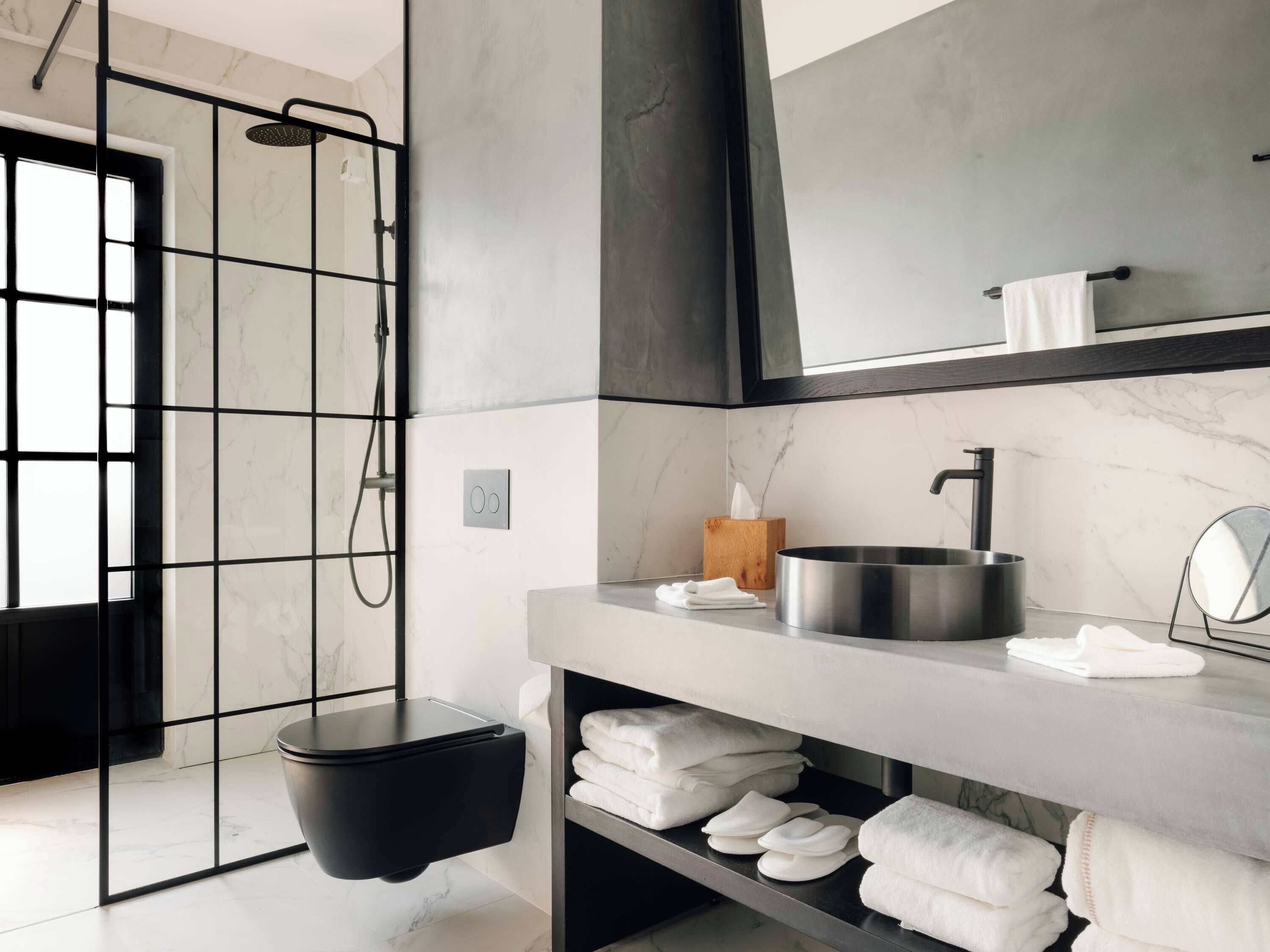 Een moderne badkamer met een douche, wastafel en spiegel.