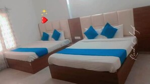 Dos camas dobles con ropa de cama azul y blanca, un cabecero de madera y una ventana con cortinas.