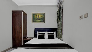 A hotel room with a bed, a wardrobe, a painting, and a curtain. - OYO 94935 Rahayu Homestay (Mangunan)
