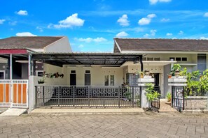 A residential building with a covered patio area, a gated entrance, and a paved driveway. - OYO 94935 Rahayu Homestay (Mangunan)