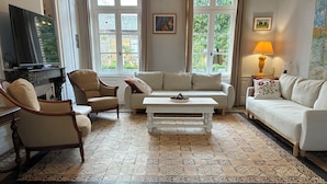 Un salon avec un canapé, des fauteuils, une table basse et un téléviseur.
