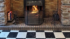 Une cheminée avec un sol à carreaux, un mur en pierre et une cheminée en bois ornée d’objets décoratifs.
