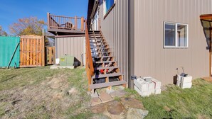 A residential building with a wooden staircase leading to a deck, a fenced yard, and construction materials on the ground. - Introvert's Perfect Hideaway: Healing Waters (Hot Springs)