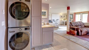 Un espace de vie compact comprenant une machine à laver et un sèche-linge intégrés, un coin cuisine, un espace salon avec un canapé et une table à manger.