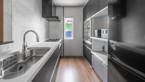 A modern kitchen with a stainless steel sink, a black range hood, and a black refrigerator. - PREGIO ASAHIKAWA (Asahikawa)