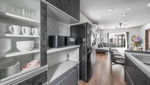 A modern kitchen with built-in appliances, a dining area with a large table and chairs, and a view into the living room. - PREGIO ASAHIKAWA (Asahikawa)