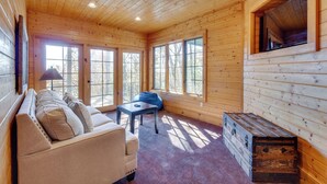 L’intérieur d’une cabane en rondins, avec un canapé, une petite table et une commode.