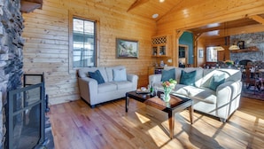 L’intérieur d’un chalet chaleureux, avec un mur en pierre, un plafond en bois et une cheminée.