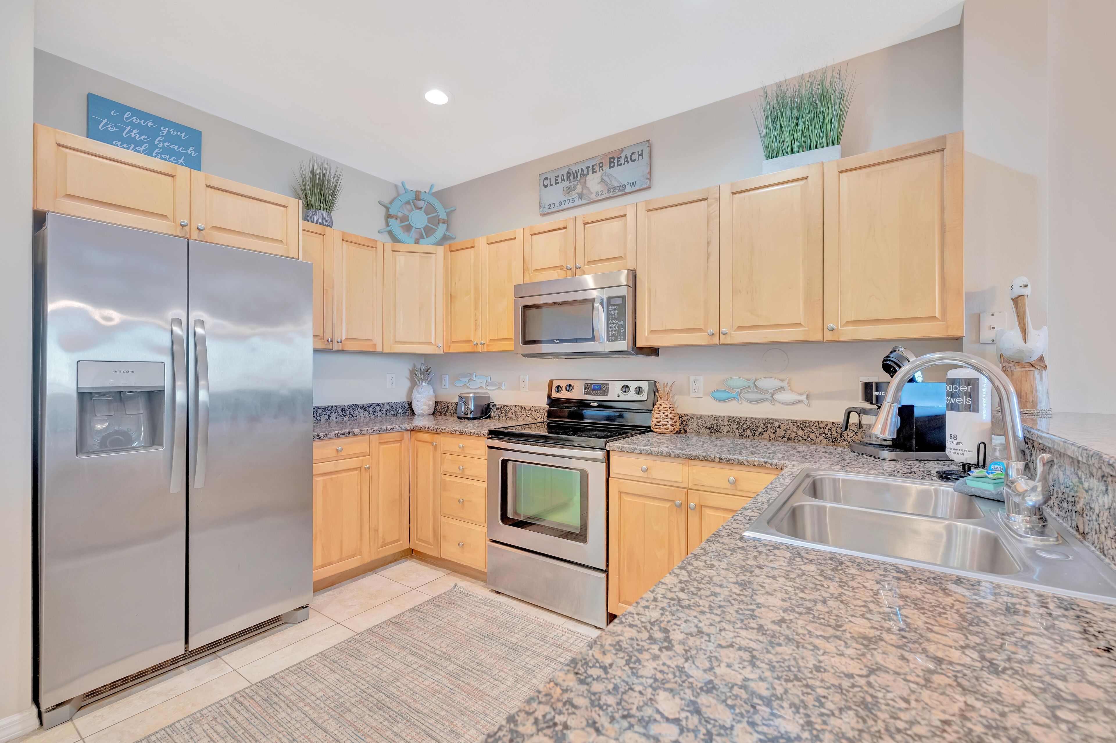 A kitchen with wooden cabinets, stainless steel appliances, granite countertops, and a sign indicating the location.