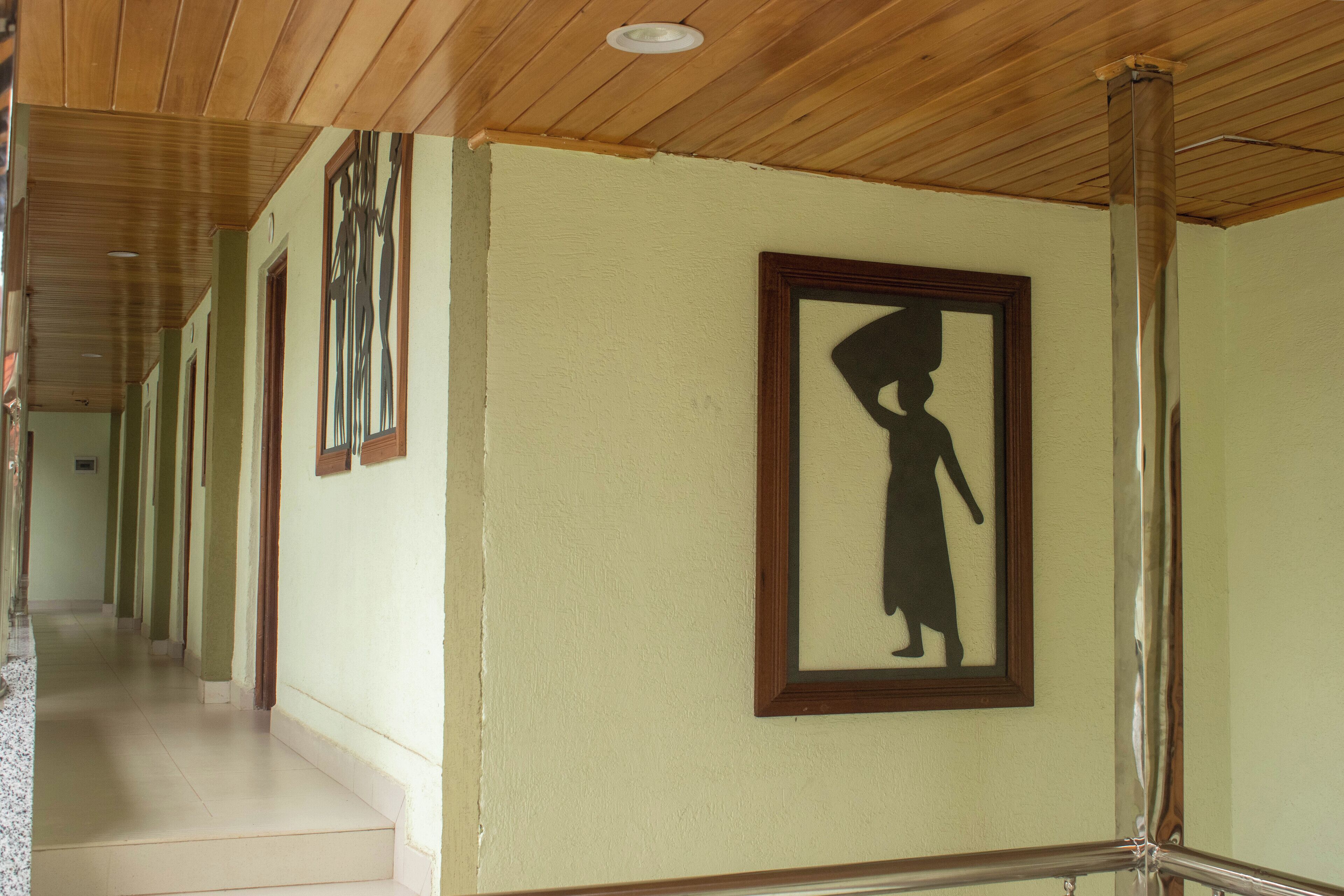 A corridor with wooden ceiling and walls, a staircase, and framed silhouettes on the walls.