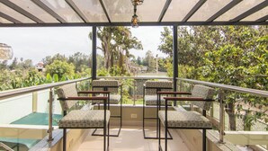 Een balkon met vier stoelen en een tafel, met uitzicht op een tuin en een gebouw.