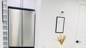 A modern kitchen with a stainless steel refrigerator, white cabinetry, and a dining area with a table and chairs. - Stylish Kinglet Gardens Stay Near Big Lake, Lois Hole Park & West Edmonton Mall (Edmonton)