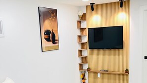 A modern living room with a grey sofa, a mounted TV, and a wooden panel wall. - Stylish Kinglet Gardens Stay Near Big Lake, Lois Hole Park & West Edmonton Mall (Edmonton)