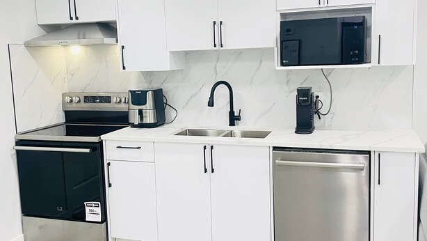A modern kitchen with white cabinets, stainless steel appliances, and a marble backsplash. - Stylish Kinglet Gardens Stay Near Big Lake, Lois Hole Park & West Edmonton Mall (Edmonton)