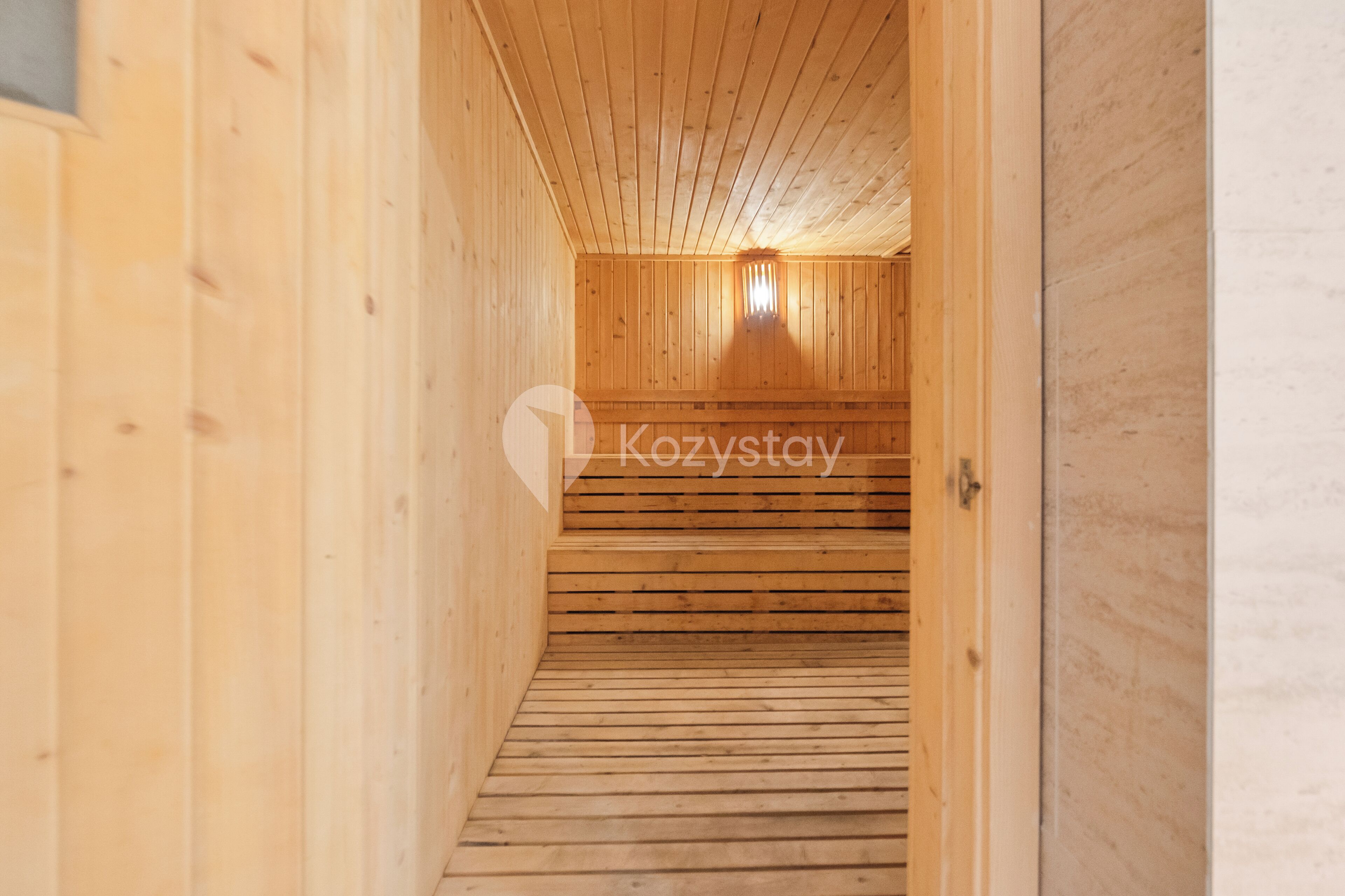 A wooden interior hallway with a wooden floor and walls, leading to a room with a window.