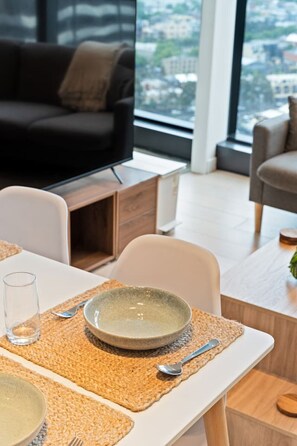 Ein zeitgemäßer Essbereich mit einem Tisch für zwei Personen, einer Schüssel, einem Glas und einem Löffel auf einer gewebten Tischunterlage.