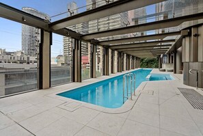 Ein Dachpool mit Glasüberdachung, umgeben von modernen Gebäuden.