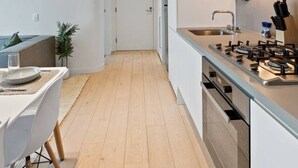 Uma cozinha moderna com ilha central, piso de madeira e área de refeições com mesa e cadeiras.