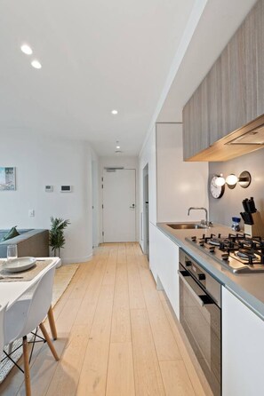 Eine moderne Küche mit einer zentralen Kochinsel, Holzböden und einem Essbereich mit Tisch und Stühlen.