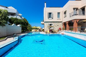 En säsongsöppen utomhuspool, parasoller och solstolar