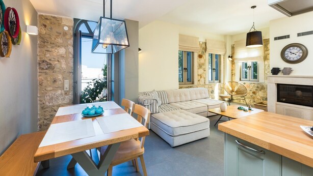A modern living room with a sofa, dining table, and kitchen area. - Philoxenia Residences (Mylopotamos)