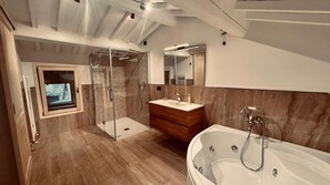Et moderne badeværelse med en glasafskærmet brusebad, et træbordplads og et fristående badekar.