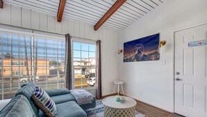 A room with a large window, a blue sofa, a round side table, and a door labeled "Beach House".