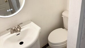 A bathroom with a white sink, a mirror, and a toilet. - Awesome 2 Bedroom in downtown (London)