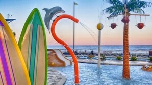 Un parque acuático con coloridas tablas de surf, una escultura de delfín y una palmera.