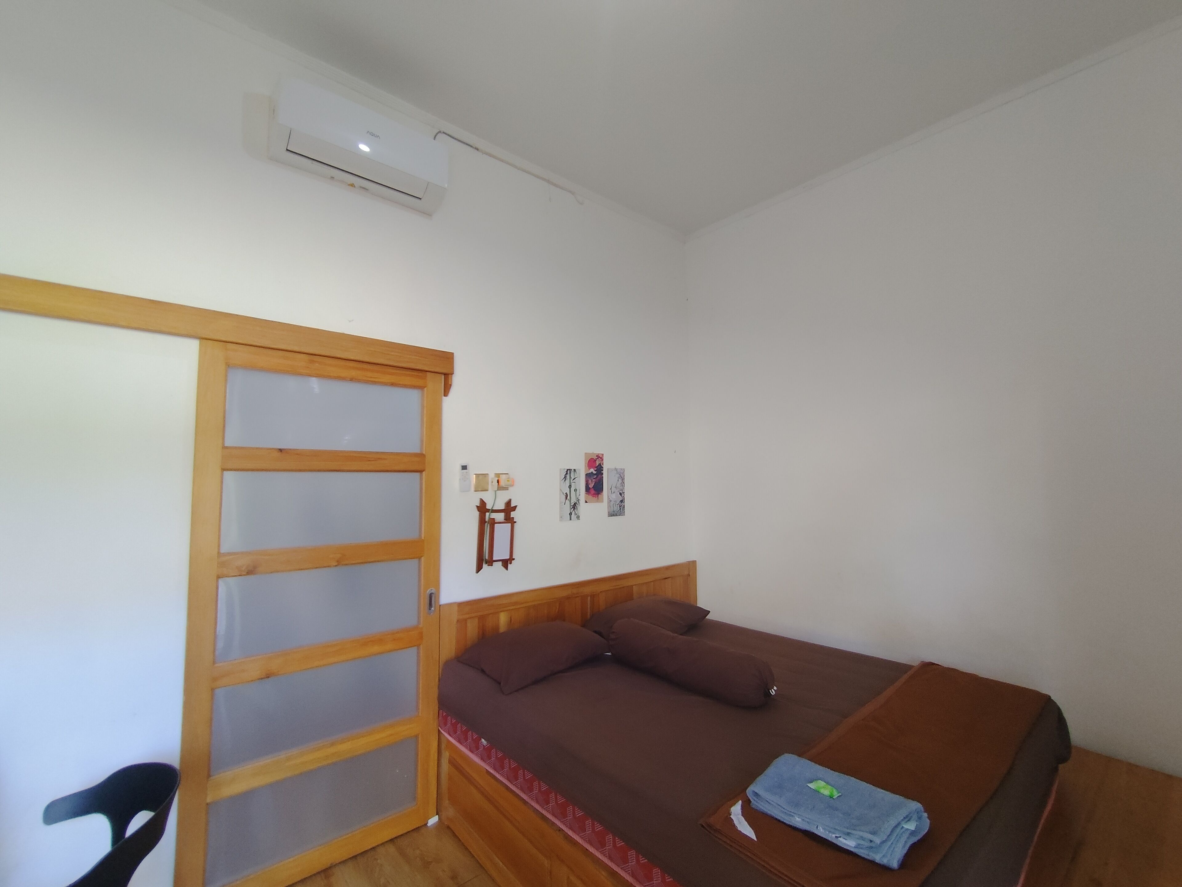 Quarto com uma cama, um guarda-roupa de madeira e um ar condicionado.