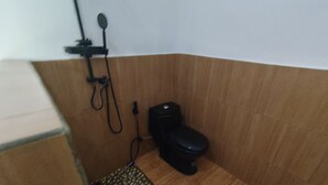 A small bathroom with a toilet, shower, and a patterned mat. - OYO 94933 Wisma Cha Tatami Palangkaraya (Palangkaraya)