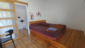 A bedroom with a bed, a chair, a small table, and a wooden bench. - OYO 94933 Wisma Cha Tatami Palangkaraya (Palangkaraya)