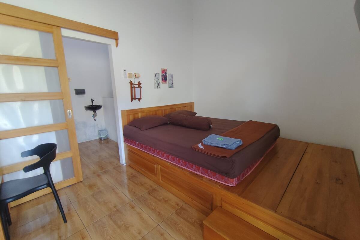 Ein Schlafzimmer mit einem Bett, einem Sessel, einem kleinen Tisch und einer Holzbank.