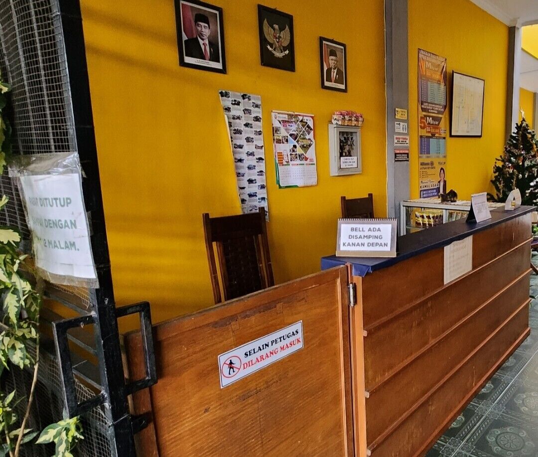 Un comptoir d’accueil en bois et un panneau indiquant l’emplacement de la salle d’attente.