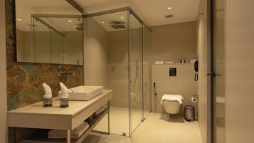 A modern bathroom with a glass-enclosed shower, a white sink, and a toilet.
