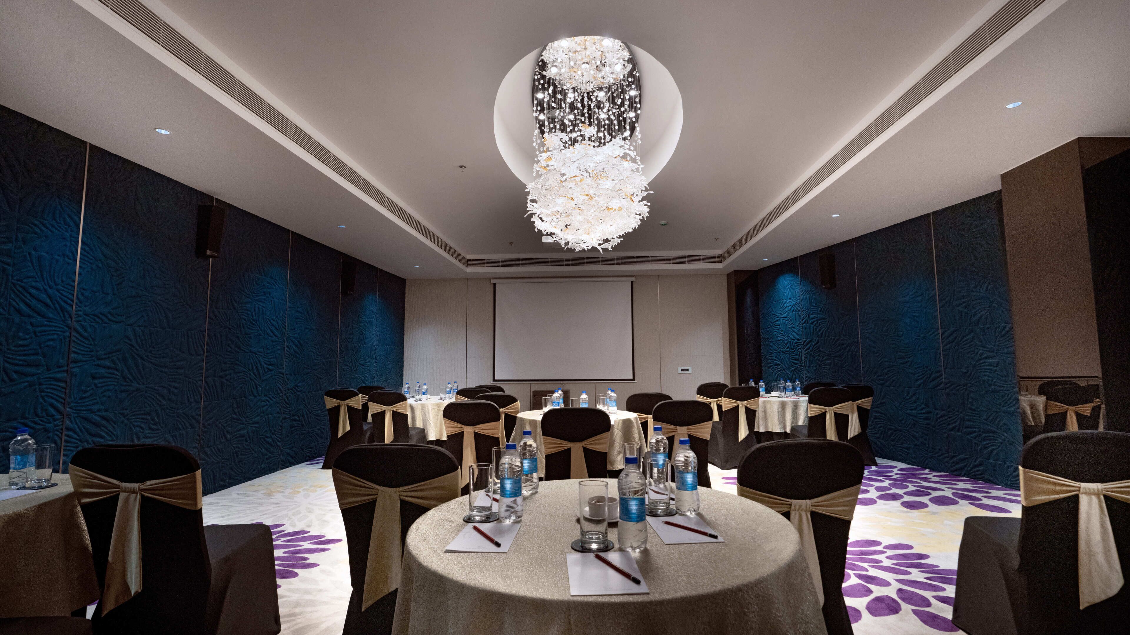 A conference room with round tables, chairs, and a large chandelier.