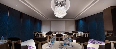 Ein Konferenzraum mit runden Tischen, Stühlen und einer großen Pendelleuchte.