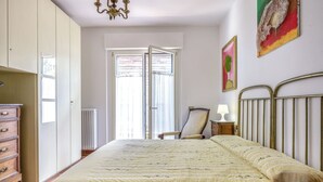 Un dormitorio con cama, cómoda, silla y una obra de arte en la pared.